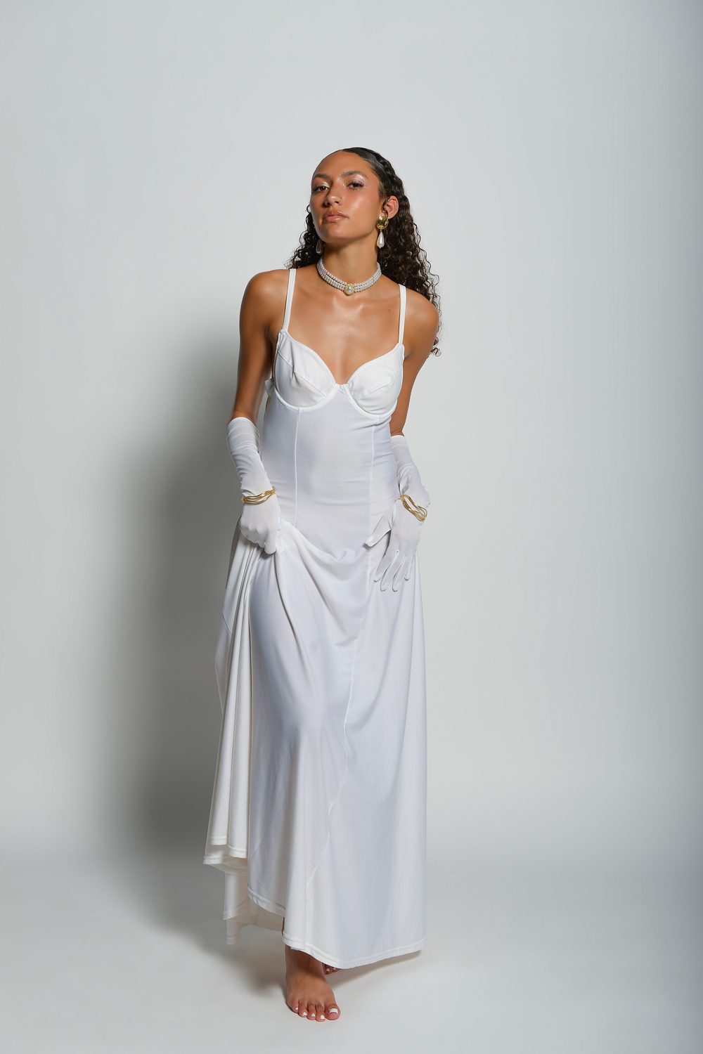 The long white dress styled for Harper’s Bazaar — bias-cut satin with a draped train and long white opera gloves, shot full length on a pale studio backdrop