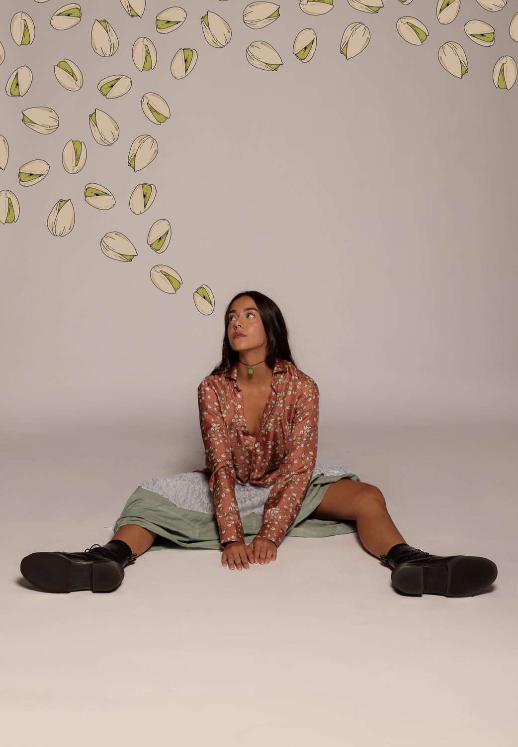 Studio frame in a pistachio-print shirt with graphic pistachio illustrations raining down across the image