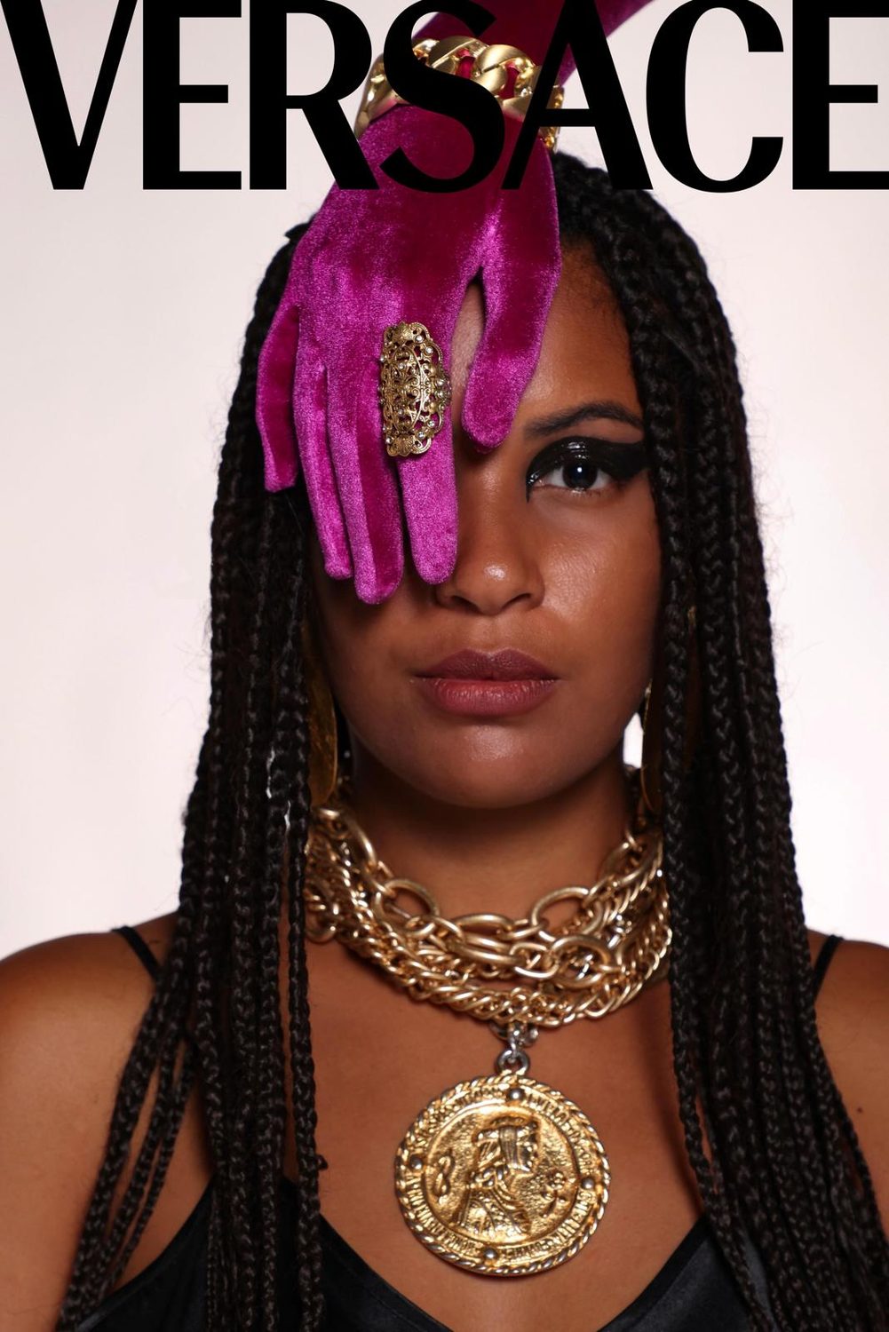 Mock cover with a magenta satin glove across one eye, heavy gold chains and a Medusa medallion